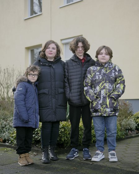 Mit ihren drei Söhnen vor deren Wohnung in einer Reihenhaussiedlung.